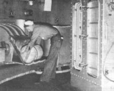 29.jpg: Матрос подает пороховой картуз на лоток зарядного элеватора, «Айова», 1943 г. Картуз весил 110 фунтов (49,9 кг), заряд одного выстрела включал 6 таких картузов